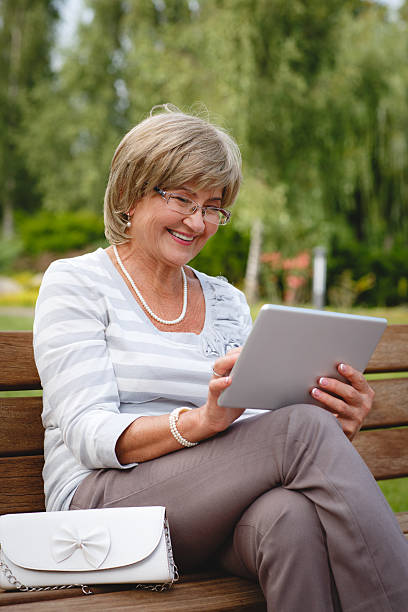 istock Attractive mature woman using digital tablet in a park 628004406