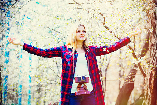 portrait of the beautiful young woman with camera near blooming cherry