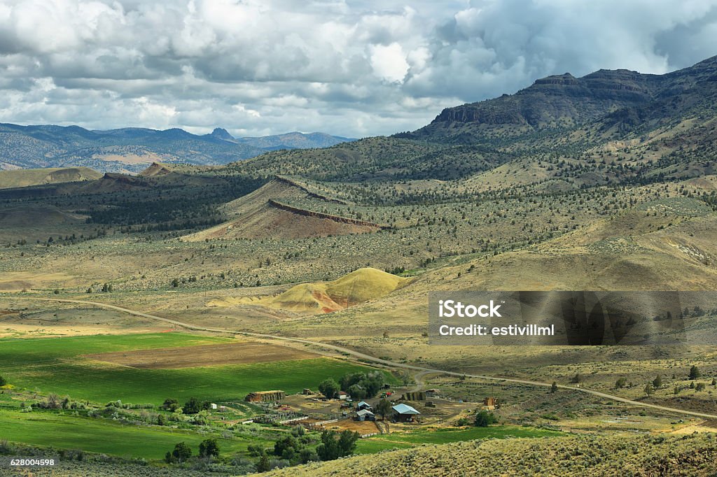 Painted Hills National Monument, USA View of a ranch and mountains from Carroll rim trail in Painted Hills National Monument in Oregon, USA Oregon - US State Stock Photo