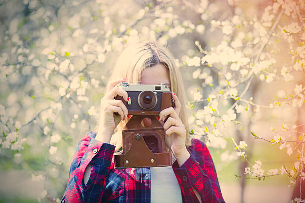 portrait of the beautiful young woman with camera near blooming cherry