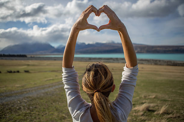 istock Young woman by the lakeshore makes heart shape finger frame 628006038
