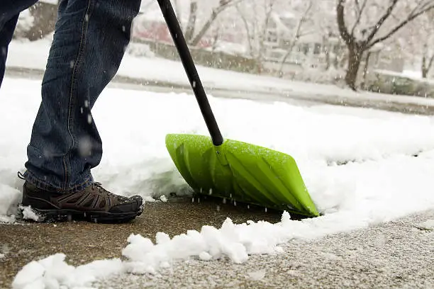 Photo of Man shoveling and removing snow in front of his house