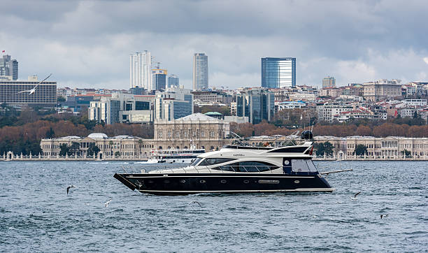 Istanbul, Turkey - November 21, 2016: Photo of a motor yacht while sailing on the bosphorus in Istanbul. Dolmabahçe Palace and skyscrapers of European side of Istanbul are seen on the background.