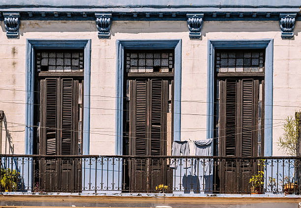 Island of Gorée, Dakar, Senegal: rough red façade and open window with open wooden blue shutters - Hesse Street, the corniche