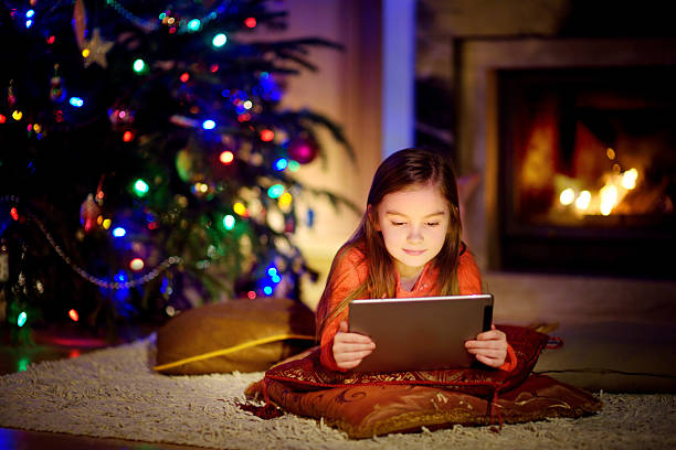 istock Adorable little girl using tablet pc by fireplace on Christmas 628023780