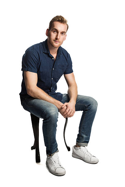 istock Man in blue shirt and jeans sitting down looking 628024588