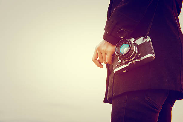 istock Young woman wearing black coat standing carry retro camera 628028062