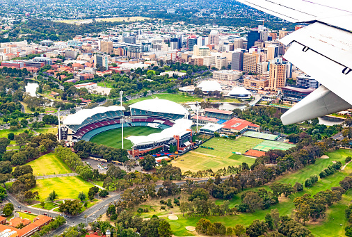 Adelaide, Australia - December 1, 2016: Aerial view of the Adelaide Oval and sporting precinct, Torrens River, city buildings, Adelaide university, Arts and Cultural precinct from an approaching commercial aircraft with parklands and leafy suburbs in the background. 