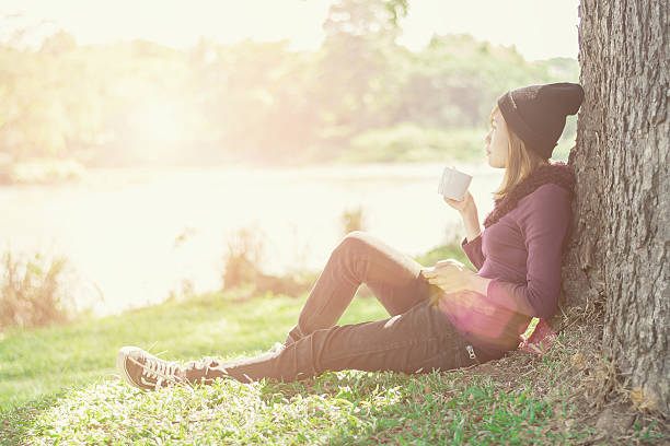istock Smiling woman with cup coffee enjoying near riverside 628032226