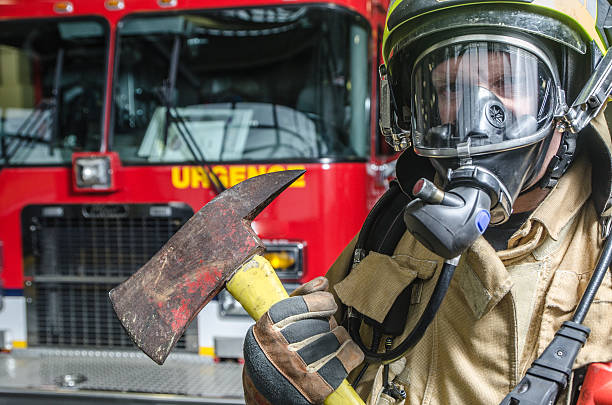 Headshot on fireman wearing full protection equipment and truck Headshot on fireman wearing full protection equipment and holding an axe in front of truck helmet hardhat protective glove safety stock pictures, royalty-free photos & images