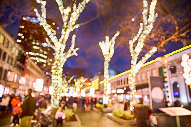 christmas lights and people walking around on the street. blurred background due to the concept