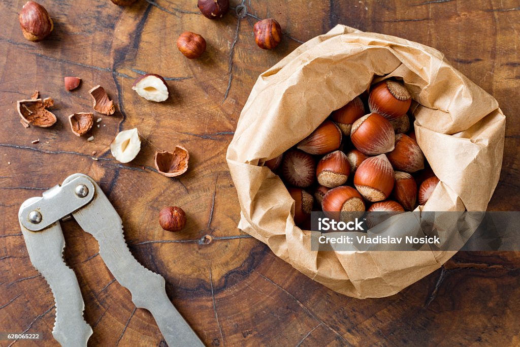 Hazelnuts in paper sack Hazelnuts, organic healthy snack and vintage nutcracker on wooden background, top view Hazelnut Stock Photo