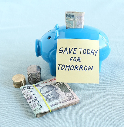 Financial concept of the need for saving money today for tomorrow indicated through a handwritten text on a note posted on a piggy bank.