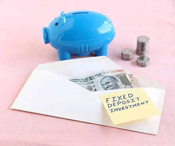 Fixed deposit investment concept indicated by the handwritten text on a paper on an envelope with Indian rupees.