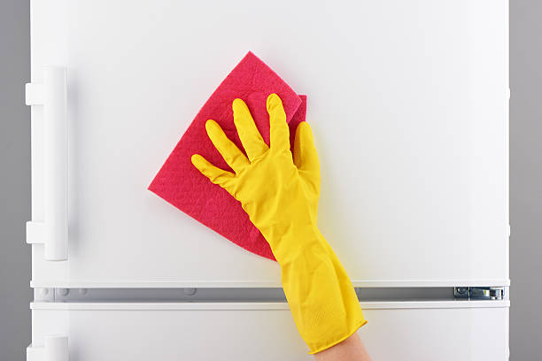 istock Hand in yellow glove cleaning refrigerator with pink rag 628078942