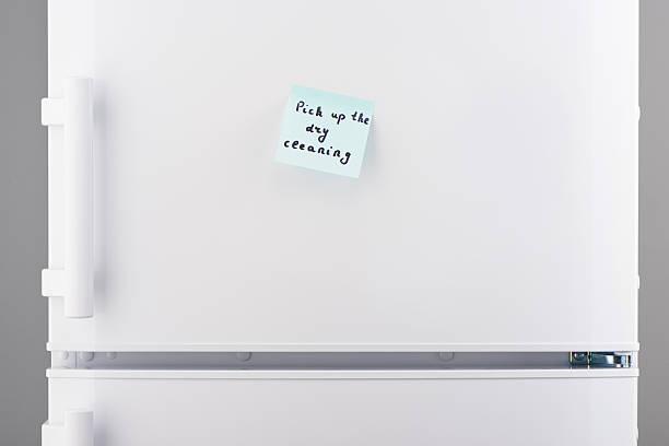 istock Pick up dry cleaning on blue notepaper on white refrigerator 628084134