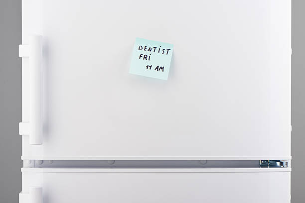 istock Dentist friday 11 am on blue notepaper on white refrigerator 628084200