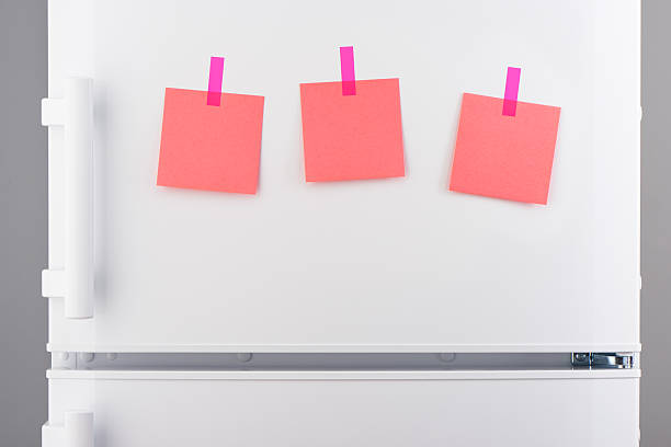 istock Pink paper notes attached with stickers on white refrigerator 628086974