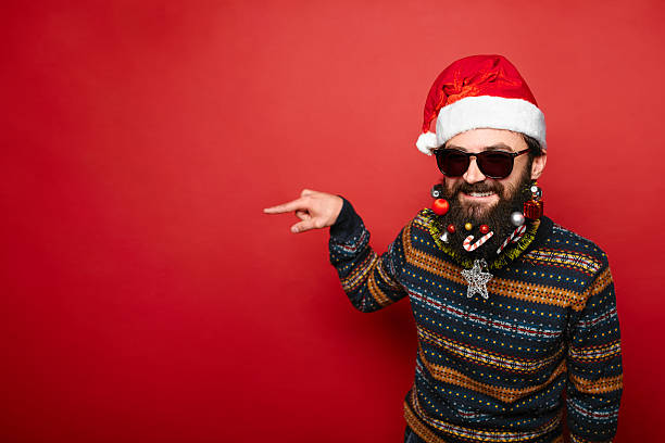 istock Young man in sunglasses and Santa hat pointing away 628087982