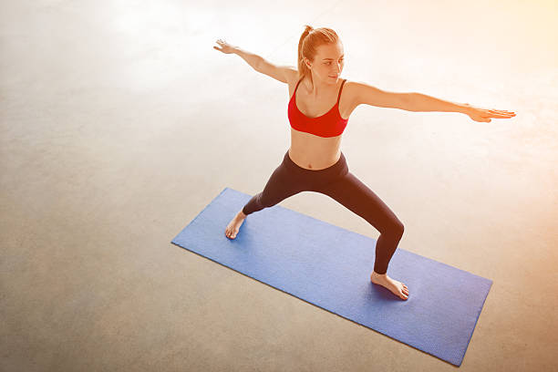 A Caucasian woman practices different yoga forms and positions in a bright well lit studio.  Here she holds Bharadvaja's Twist, or Sage pose.  Horizontal with copy space.