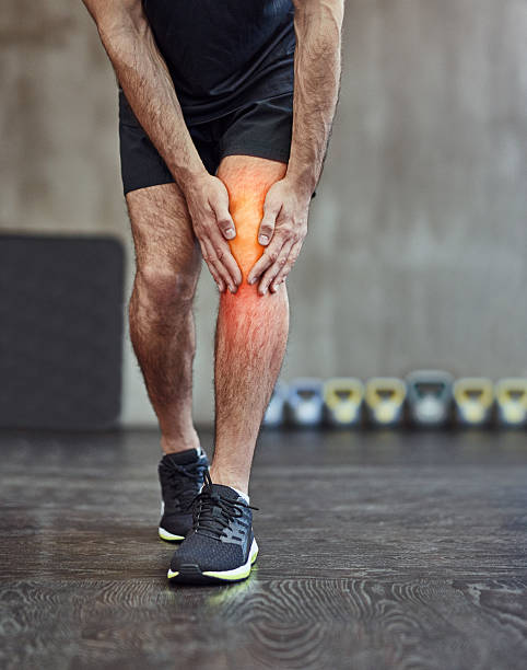 Injuries are just a part of the package Shot of an unrecognizable man holding his knee in pain standing had to knee pose stock pictures, royalty-free photos & images