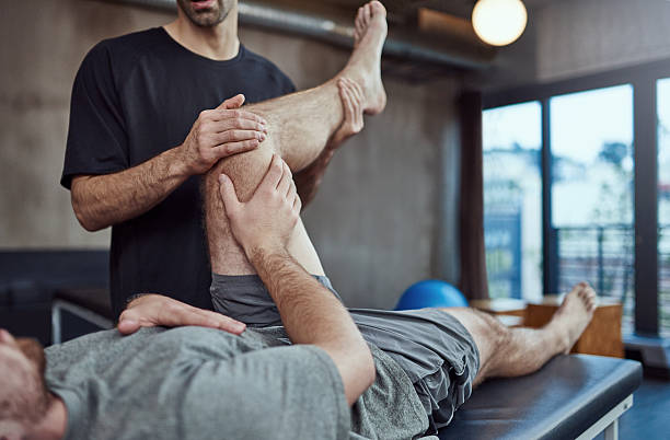 Just a little more... Shot of a young man visiting his physiotherapist for a rehabilitation session touch sensitive stock pictures, royalty-free photos & images