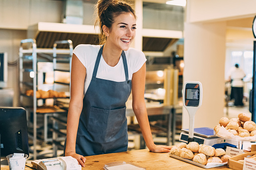 Smiling young baker at the checkout counter.