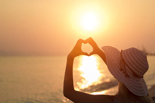 istock Woman with hands create 'heart' shape over sea, ocean, sunrise 628093080