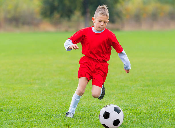 istock Boy kicking soccer ball 628096018
