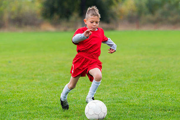 istock Boy kicking soccer ball 628096414