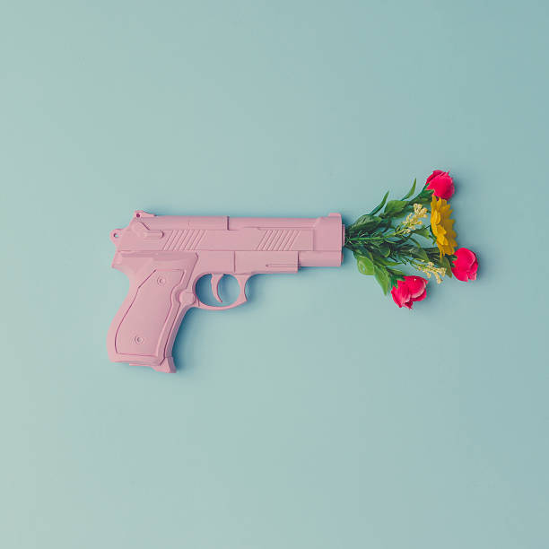 istock Pink hipster handgun on blue pastel background with flowers. Pie 628097136