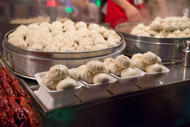 Chinese dumplings (dim sum) sold by market vendor at the Donghuamen Night Market - the most popular snack street in Beijing - located at the northern entrance of Wangfujing Street. The vendors are preparing and selling deep fried meat and seafood - including some exotic foods such as silkworm and snakes - served on a stick, but also more ordinary foods like bread, noodles, fruit, vegetables and soft drinks. The image was captured at night in low light (at high ISO).