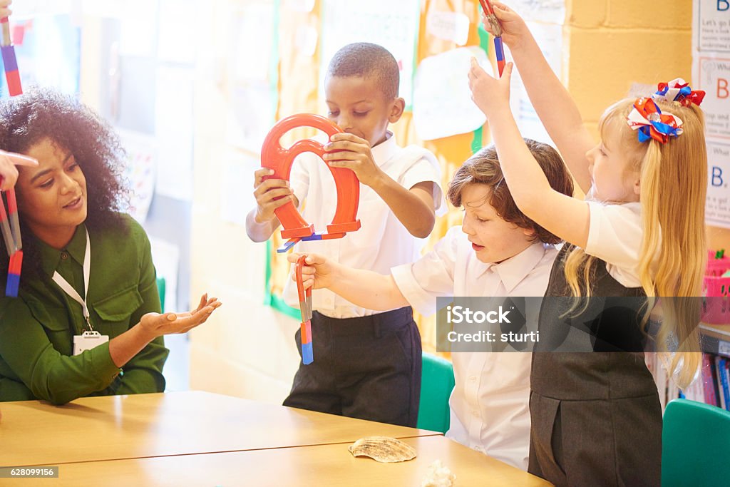 magnetic field science primary aged schoolchildren sit at their desks and play with various magnets as they discover science with their teacher . Magnet Stock Photo
