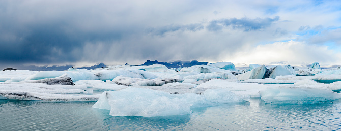 Icebergs floating  in the Jokulsalon glacier lagoon in Iceland with the mountains and Vatnajökull glacier in the distant background.