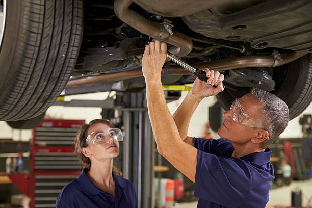 istock Male And Female Mechanics Working Underneath Car Together 628110704