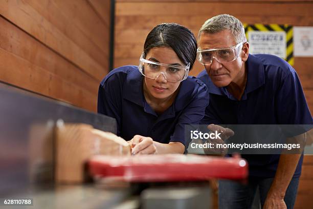 Carpenter Training Female Apprentice To Use Plane Stock Photo - Download Image Now - Trainee, Carpenter, Carpentry