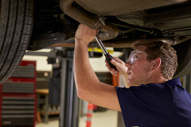 auto mechanic working underneath car in garage - trainee working car mechanic imagens e fotografias de stock