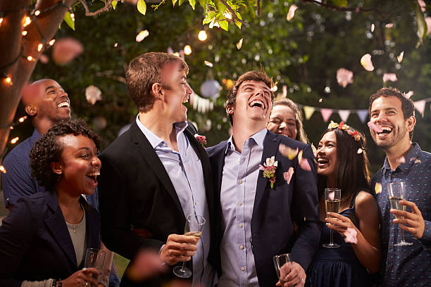 Gay Couple Celebrating Wedding With Party In Backyard Gay Couple Celebrating Wedding With Party In Backyard gay man photos stock pictures, royalty-free photos & images