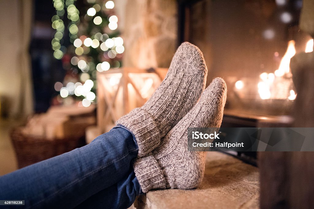 Feet of unrecognizable woman in socks by the Christmas fireplace Feet of unrecognizable woman in woollen socks by the Christmas fireplace. Winter and Christmas holidays concept. Christmas Stock Photo