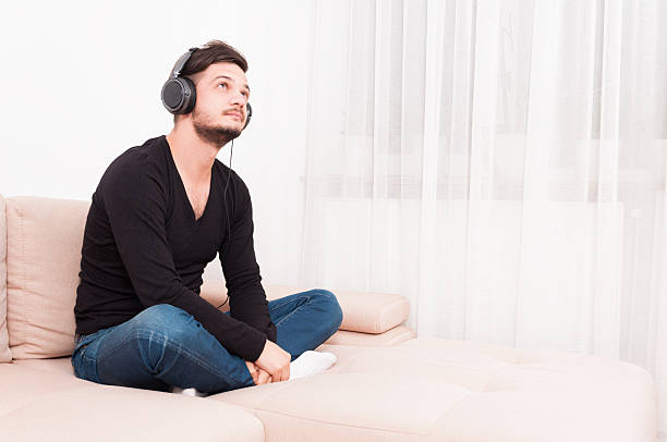 istock Man sitting on sofa wearing headphones and relaxing 628120338