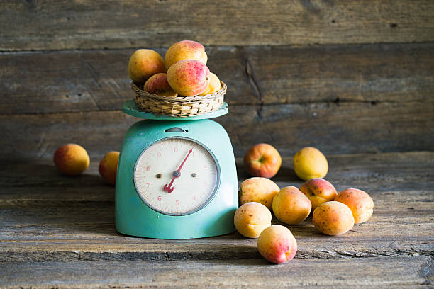 Apricots with kitchen scales on a wood background. toning. Veget Apricots with kitchen scales on a wood background. toning. Vegetarian food. Healthy life. vintage kitchen scale with fruit stock pictures, royalty-free photos & images