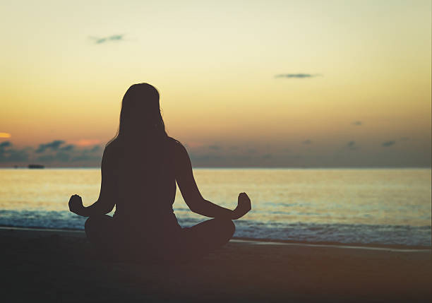 istock young woman meditation on sunset beach 628121360