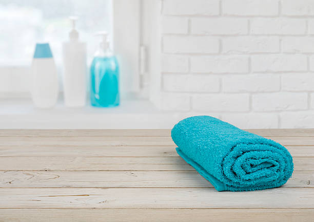 folded towel on wooden planks over defocused brick wall window - liquid soap blue plastic textile imagens e fotografias de stock