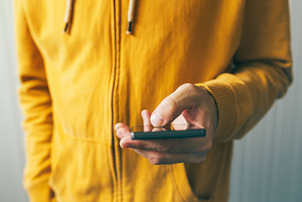 istock Young man in yellow shirt using smartphone 628127366