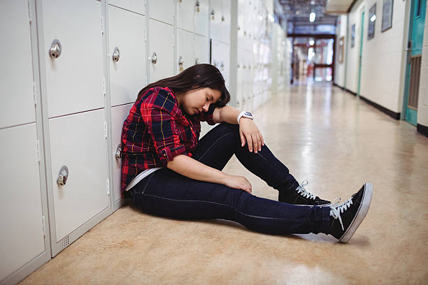 istock Depressed female student sitting in locker room 628132746