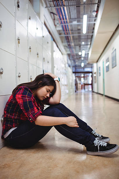 istock Depressed female student sitting in locker room 628132814