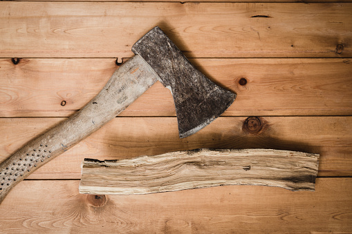 Old ax and chipped branch on a wooden table