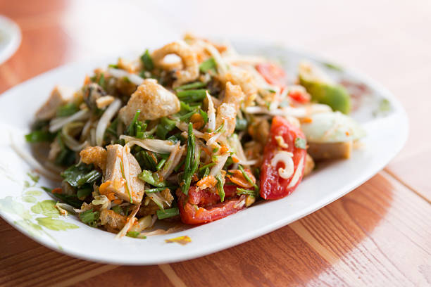 hot and spicy Thai papaya salad with fried pork skin or somtam, popular local dish for food background