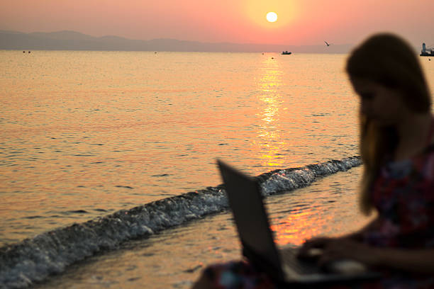 istock Woman at beach working on laptop. Selective focus on sea. 628137688