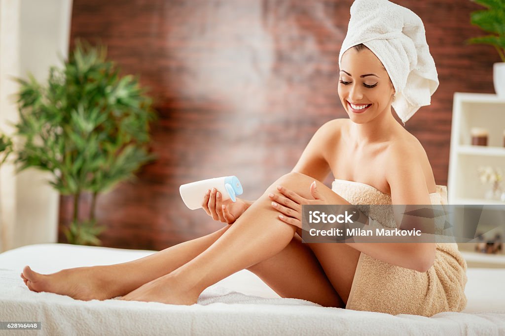 Body Care Beautiful young woman applying body lotion. The Human Body Stock Photo